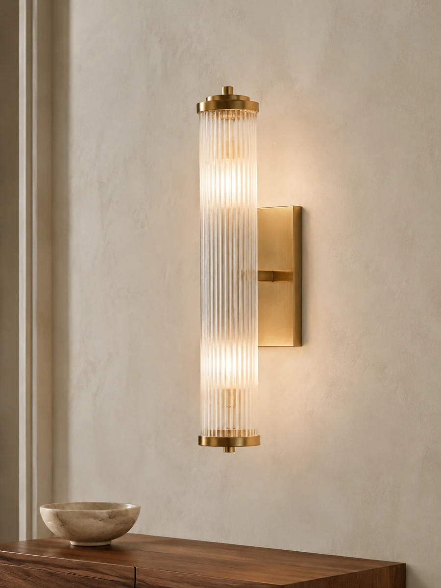 Brass wall sconce with fluted glass on a light textured wall.