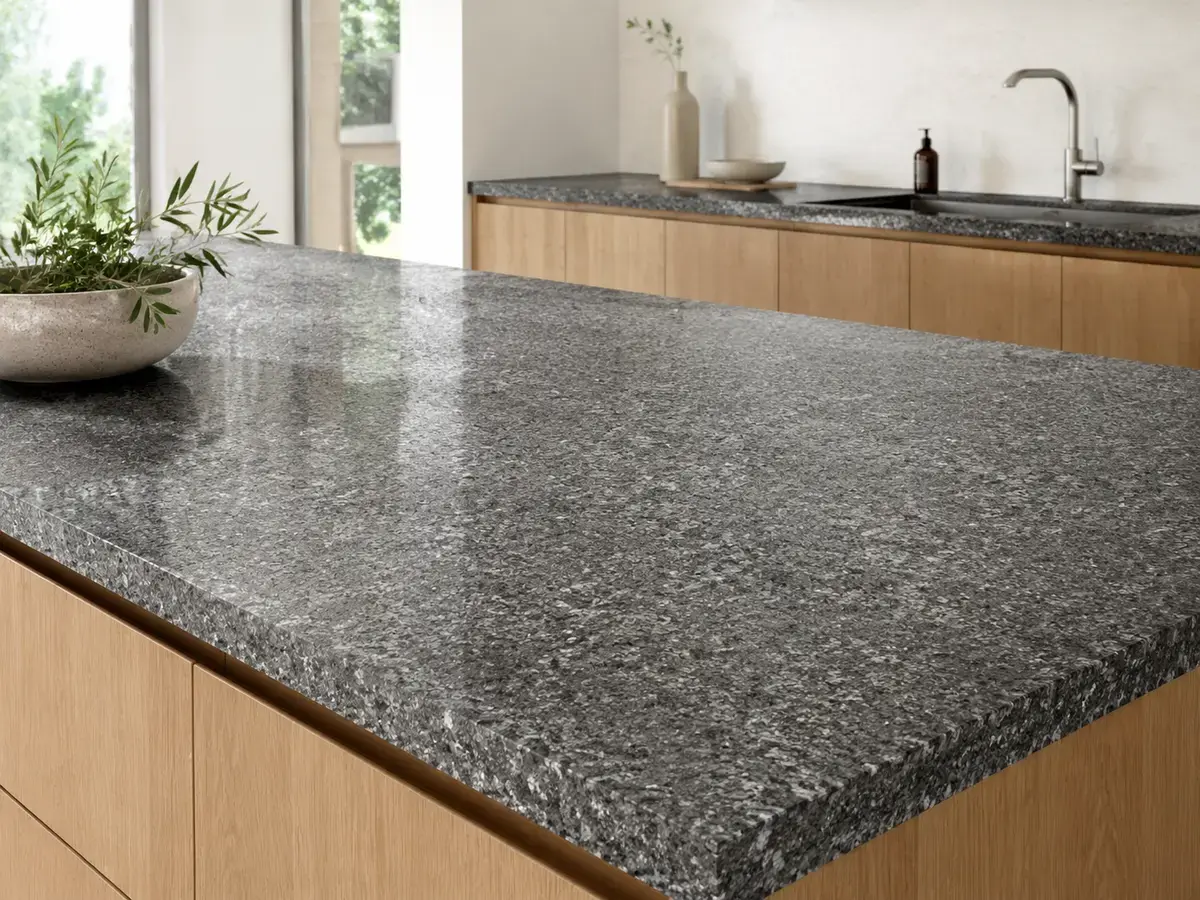 Gray granite kitchen countertop with speckled mineral patterns and light wood cabinetry.