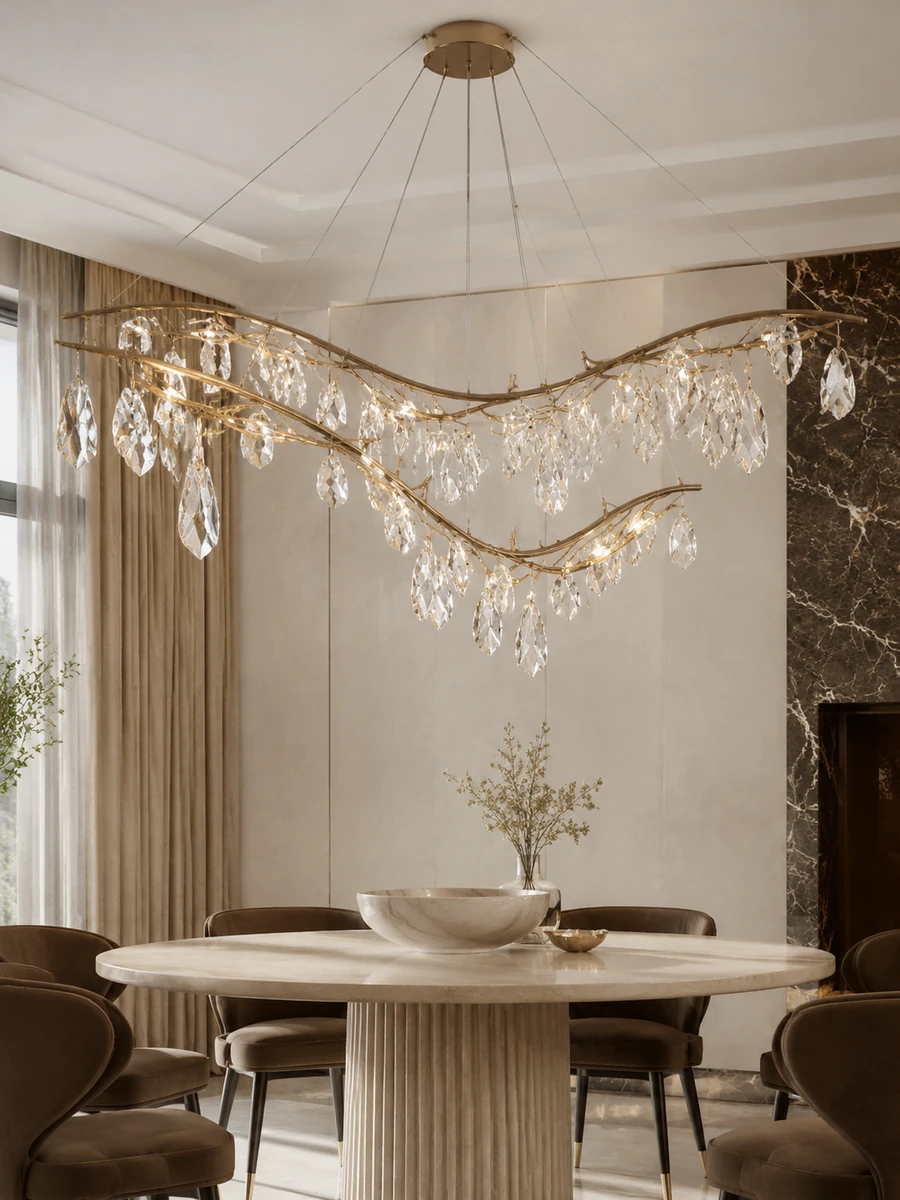 Luxury lighting featuring a sculptural gold chandelier with crystal leaves above a stone table.