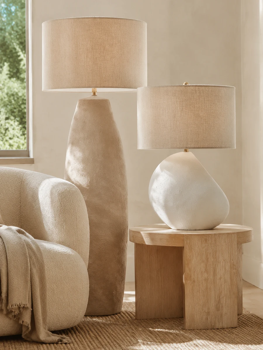 Organic modern lighting with textured ceramic lamps and linen shades beside curved neutral seating.